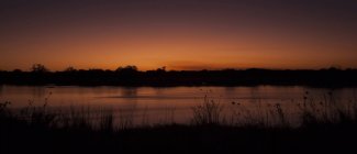 Намибия, закат в Окаванго над полем и озером — стоковое фото