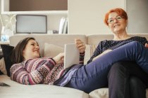 Mère et fille adulte avec tablette numérique sur le canapé — Photo de stock