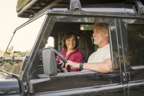Happy senior couple on a trip in a cross country vehicle — Stock Photo