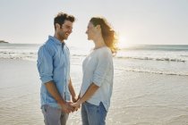 Портрет улыбающейся пары, стоящей на пляже — стоковое фото