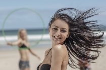 Счастливая молодая женщина на пляже с друзьями на заднем плане — стоковое фото