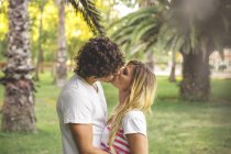 Молодая пара целуется в парке — стоковое фото