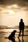México, Nayarit, silhueta de jovem com seu cão em uma coleira em uma praia ao pôr do sol — Fotografia de Stock