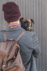 Hombre sosteniendo perro pug mirando por encima del hombro - foto de stock