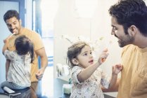 Toddler daughter playing with toothbrush washing her father teeth — Stock Photo