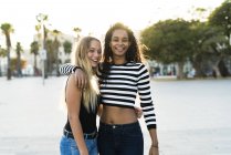 Portrait of two happy young women standing on square at sunset — Stock Photo