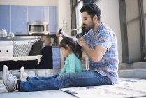 Father sitting on floor and doing haircut for daughter — Stock Photo