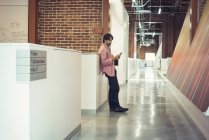 Homme d'affaires debout couloir lecture messages — Photo de stock