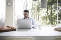 Человек, сидящий за компьютером в современном офисе бетона — стоковое фото