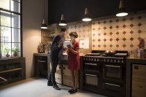 Пара стоячи на кухні і використовуючи цифровий планшетний — стокове фото
