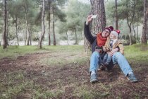 Father and son taking a selfie with smartphone in forest — Stock Photo