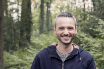 Портрет улыбающегося мужчины, стоящего в лесу — стоковое фото