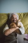 Donna anziana seduta sul divano e abbracciare gattino — Foto stock