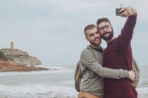 España, Oropesa del Mar, pareja gay tomando selfie frente al mar - foto de stock