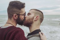 Gay couple kissing in front of the sea — Stock Photo