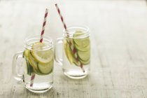 Bicchieri di acqua infusa con lime, limone, cetriolo e cubetti di ghiaccio — Foto stock