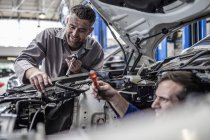 Deux mécaniciens automobiles dans un atelier de réparation de voiture ensemble — Photo de stock