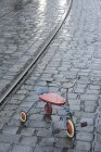 Triciclo de niños viejos sobre pavimento lluvioso - foto de stock