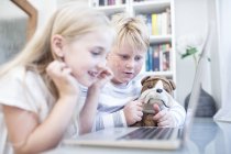 Brother and sister with cuddly toy using laptop together — Stock Photo