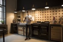 Mann steht in der Küche und benutzt Tablet — Stockfoto