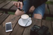 Mulher derramando açúcar na xícara de café — Fotografia de Stock