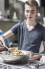 Männlicher Teenager kocht selbstbewusst im Kochkurs — Stockfoto