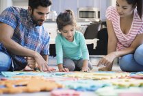 Happy family sitting on floor and playing with daughter — Stock Photo
