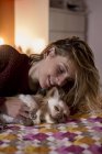 Donna sdraiata sul letto a giocare con il suo cane — Foto stock