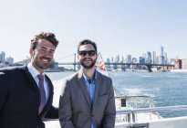 Dos hombres de negocios sonrientes en ferry en East River, Nueva York, EE.UU. — Stock Photo