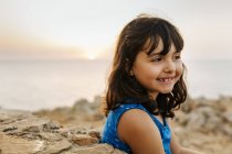 Portrait of happy little girl near the sea at sunset — Stock Photo