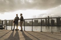 Zwei junge Männer im Gespräch am East River, New York City, USA — Stockfoto