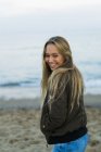 Glückliche junge Frau steht am Strand — Stockfoto