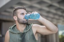 Спортсмен, узявши перерву в місті питної води з пляшки — стокове фото