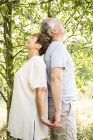 Couple aîné debout dos à dos dans un jardin verdoyant — Photo de stock