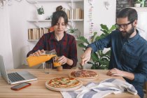 Молода пара їдять піцу і пити сік на обід — стокове фото