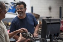 Deux mécaniciens souriants parlent en atelier — Photo de stock