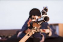 Mujer con un rifle deportivo apuntando en un campo de tiro - foto de stock