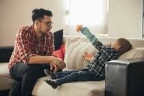 Padre e figlio giocano insieme sul divano — Foto stock