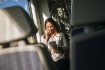 Smiling woman sitting in train and using a tablet — Stock Photo