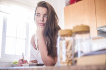 Young woman in kitchen thinking — Stock Photo