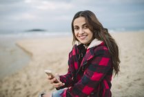 Молода жінка з смартфоном на пляжі. — стокове фото