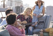 Woman playing guitar for friends at rooftop party, Los Angeles, USA — Stock Photo