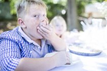 Portrait of boy eating at garden table — Stock Photo