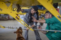Mechaniker mit Hund in Hangar repariert Leichtflugzeug — Stockfoto