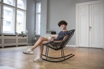 Portrait of smiling young woman sitting on rocking chair at home — Stock Photo