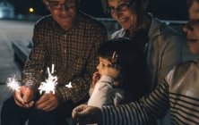 Großeltern mit Enkeln, die nachts Wunderkerzen in der Hand halten — Stockfoto