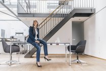 Empresária com cabelos longos e grisalhos sentada na mesa no escritório — Fotografia de Stock
