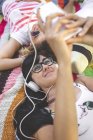 Giovane donna con gli amici sdraiata su una coperta ad ascoltare musica — Foto stock