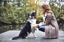 Smiling woman with her dog on jetty in autumn — Stock Photo