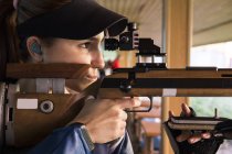 Женщина со спортивной винтовкой в тире — стоковое фото